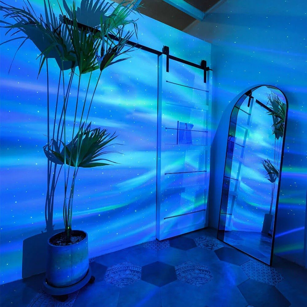 Plantes en pot et miroir dans un intérieur moderne avec porte coulissante, éclairés par une projection d'aurore boréale bleue.
