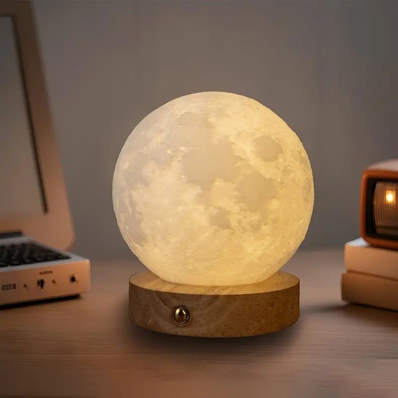 Lampe lune de couleur jaune chaleureuse sur une base en bois avec bouton, posée sur une table à côté d'un appareil audio ou TV vintage.